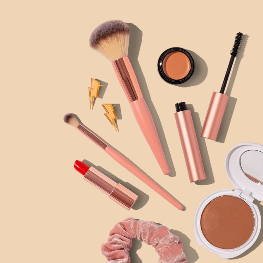 Pincéis, batom e produtos de maquiagem em tons coral